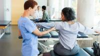 Occupational therapist checking patient's shoulder and arm alignment.